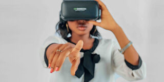 A young woman wearing a VR headset pointing at the camera